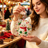 A woman holds a finished Christmas ornament made of pearl and diamond painting on a string.