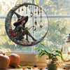 A witch figure with a pointed hat is suspended in a circular stained glass window decoration.