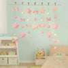 Pink tassel door curtain decorated with heart and star shapes hanging in a light blue room.