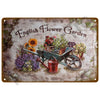 Vintage metal tin sign depicting an English flower garden with potted plants and a watering can.