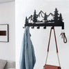 A black metal mountain forest silhouette key holder with hooks mounted on a white wall.