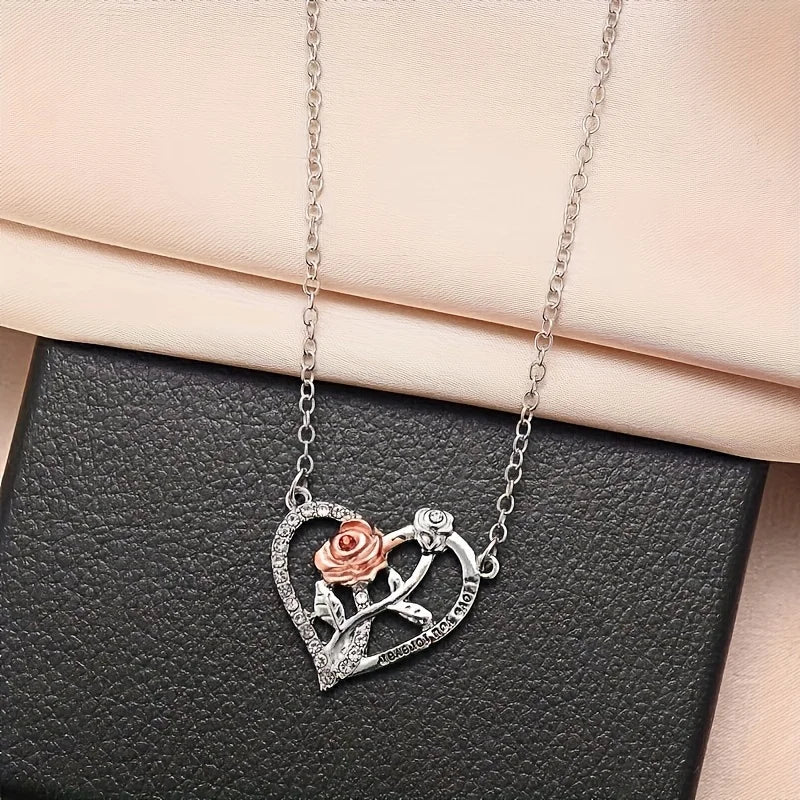 Silver heart-shaped pendant featuring a rose and bear design displayed on a black gift box.