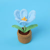 Handcrafted crochet blue tulip flower with an orange center growing in a brown pot.