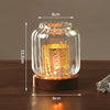 A vintage wooden candle lantern with a glass cover glowing warmly on a dark wooden surface.