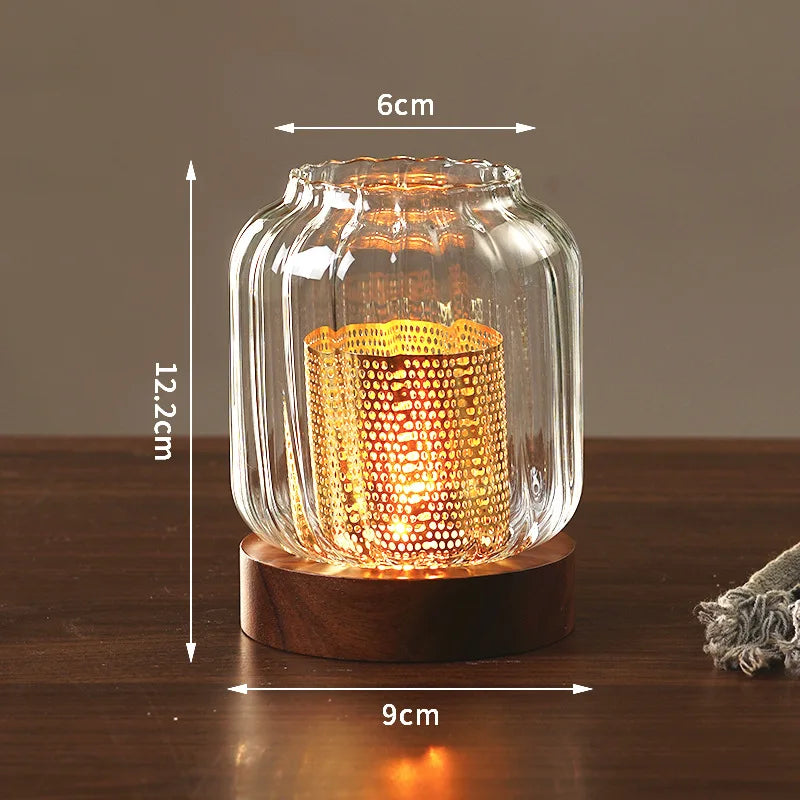 A vintage wooden candle lantern with a glass cover glowing warmly on a dark wooden surface.