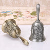 An ornate brass hand call bell with a decorative floral design is shown on a white surface.