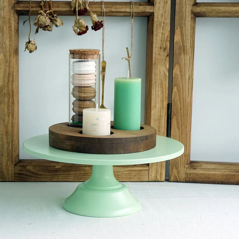A metal cake stand displaying a glass jar filled with stacked cookies and a green candle.