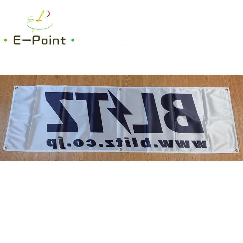 A white double-sided polyester banner featuring the text BLITZ.co.nz and www.blitz.com on a wooden surface.