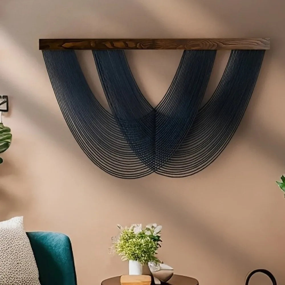 A dark blue macrame wall tapestry with a wooden bar hangs on a beige wall.