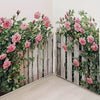 A watercolor floral decal featuring pink roses and green foliage on a weathered wooden fence wall.