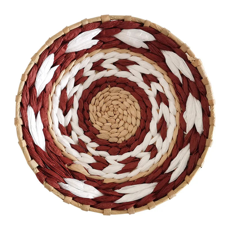 Round woven straw wall decor hanging featuring concentric rings of reddish-brown, white, and tan fibers.