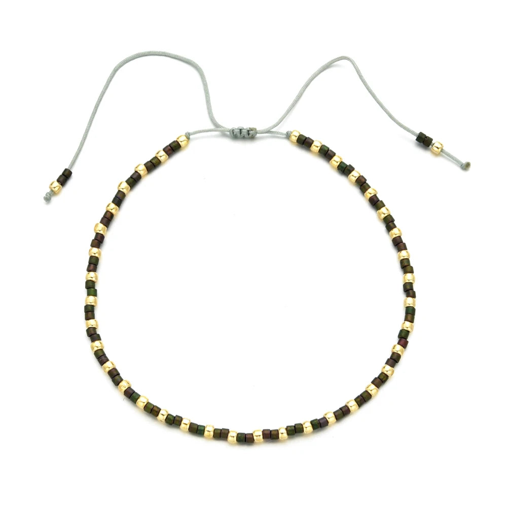 Handmade boho glass bead bracelet with adjustable cord featuring dark brown and gold beads.