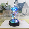 Une rose de verre éternelle avec une lumière LED bleue est exposée sur une base noire sur un fond flou.