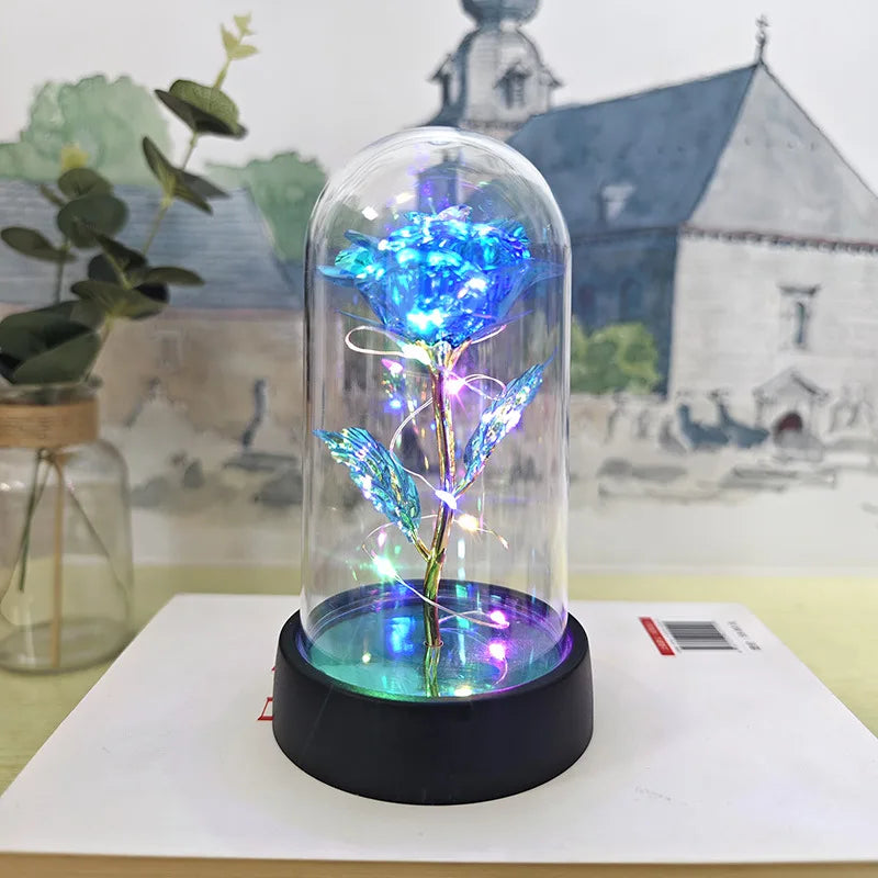 Une rose de verre éternelle avec une lumière LED bleue est exposée sur une base noire sur un fond flou.