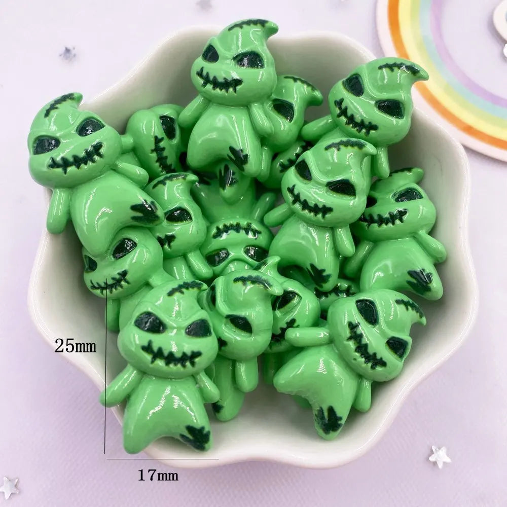 A set of small, green resin flatback cabochon figurines with skull faces displayed in a white bowl.