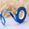 A roll of blue satin balloon ribbon unwinding against a background of light cream flowers.