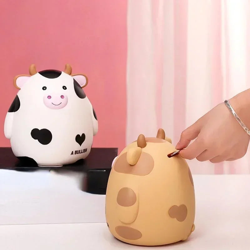 A cute, round, light yellow cartoon cow figure is shown next to a hand writing on a similar-shaped object.