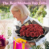 A woman presents a bouquet of red glitter artificial roses and a pink gift to a mother.