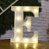 A glowing white alphabet letter E made of LED lights resting on a wooden surface.