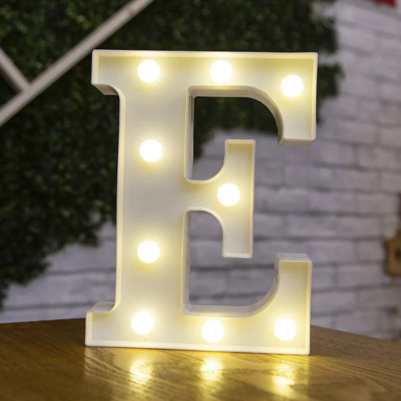 A glowing white alphabet letter E made of LED lights resting on a wooden surface.