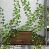 Artificial ivy vine garland cascading over a wooden planter on a gray wall.