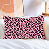 A pink leopard print decorative pillow cover lying on white bedding.