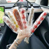 A hand holds a bundle of clear cellophane gift bags filled with various candies and treats in a car interior.