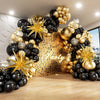 An elegant balloon garland arch featuring black and gold balloons with starburst foil accents.