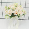 Elegant white silk rose bridal bouquet with green foliage tied with a sheer ribbon