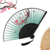 A vintage bamboo folding fan with a light green and black striped design featuring red floral accents.