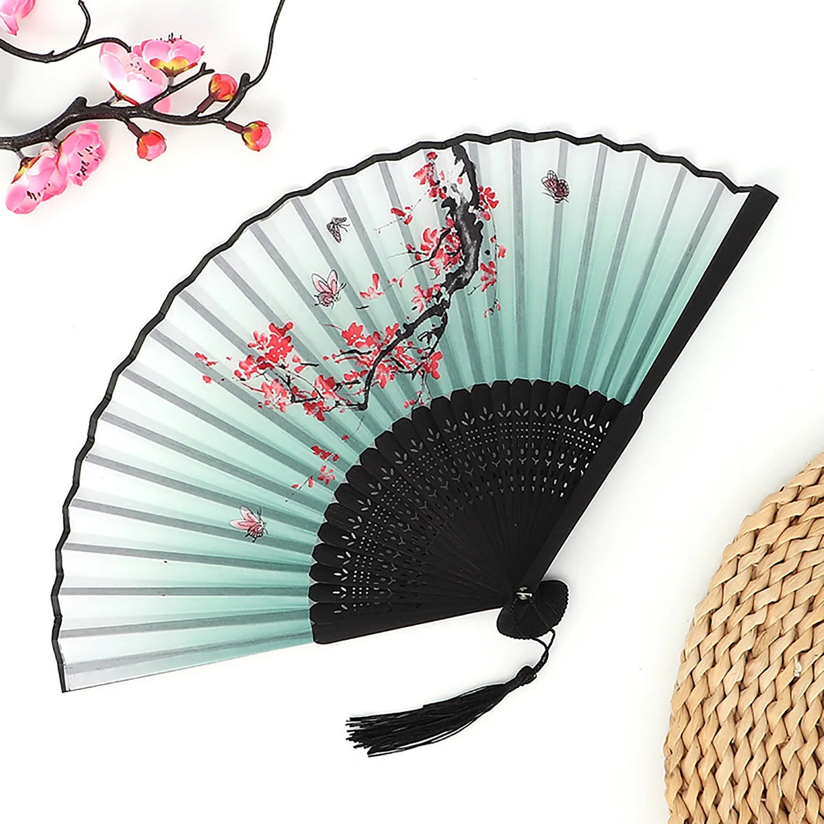 A vintage bamboo folding fan with a light green and black striped design featuring red floral accents.