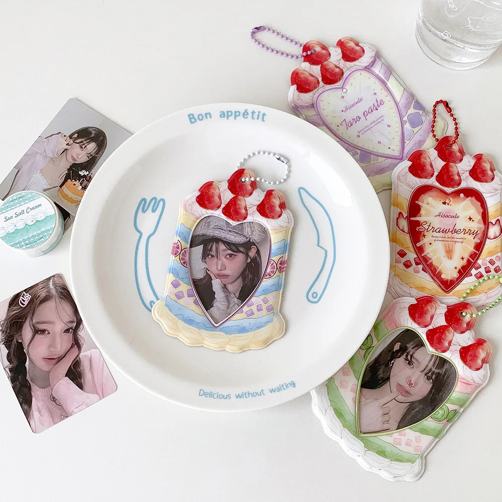 A white plate holds a strawberry-themed card holder and a bag keychain featuring strawberries and a portrait.