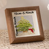 A wooden photo frame displaying a green Christmas tree cutout on a light background.