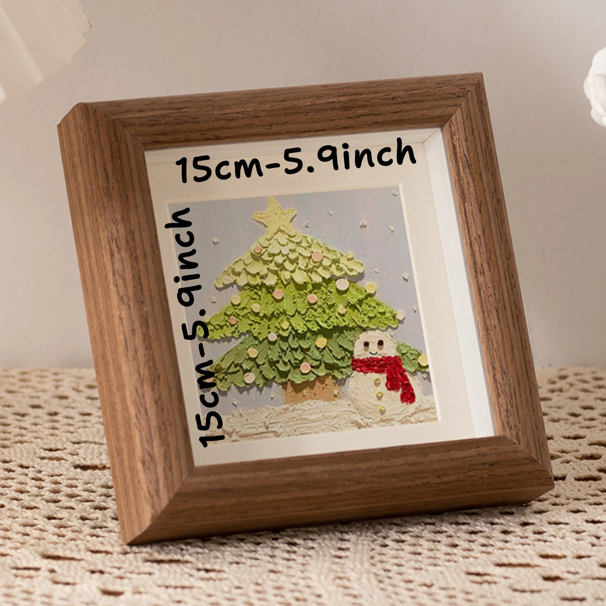 A wooden photo frame displaying a green Christmas tree cutout on a light background.