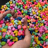 A close-up shot of many colorful miniature resin flamingo and duck figurines scattered on a hand.