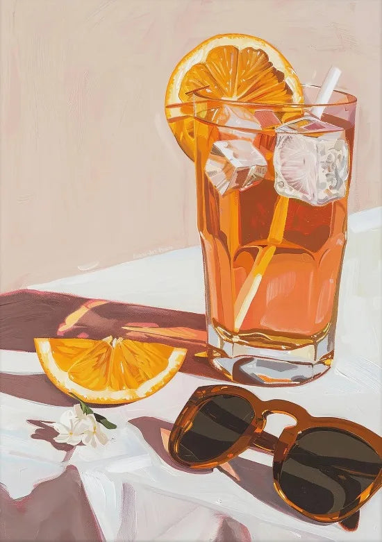 A glass of orange juice with ice and a lemon slice sits on a white surface.