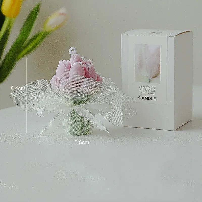 A pink tulip bouquet in a glass vase next to its retail box for a healing life soy wax candle