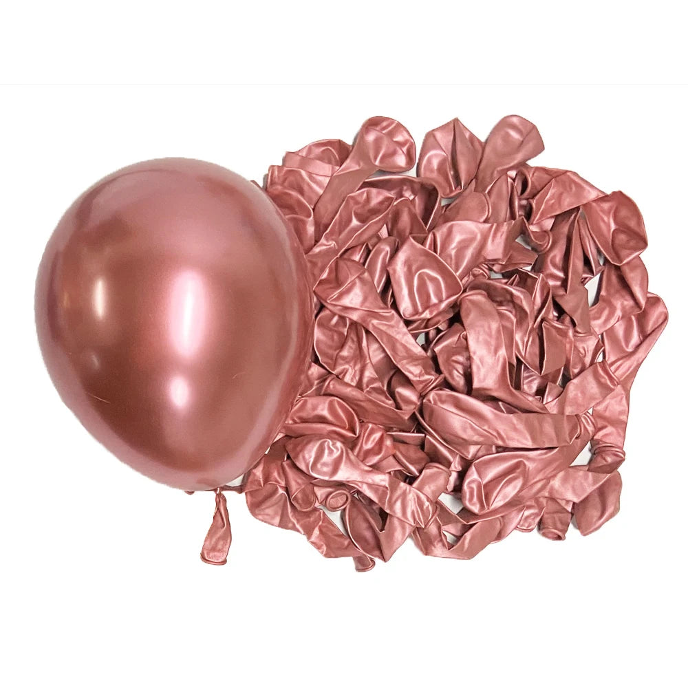 A single rose gold metallic latex balloon next to a pile of crumpled rose gold metallic latex balloons.