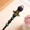 A black crystal scepter topped with a purple amethyst bee, featuring various colored beads.