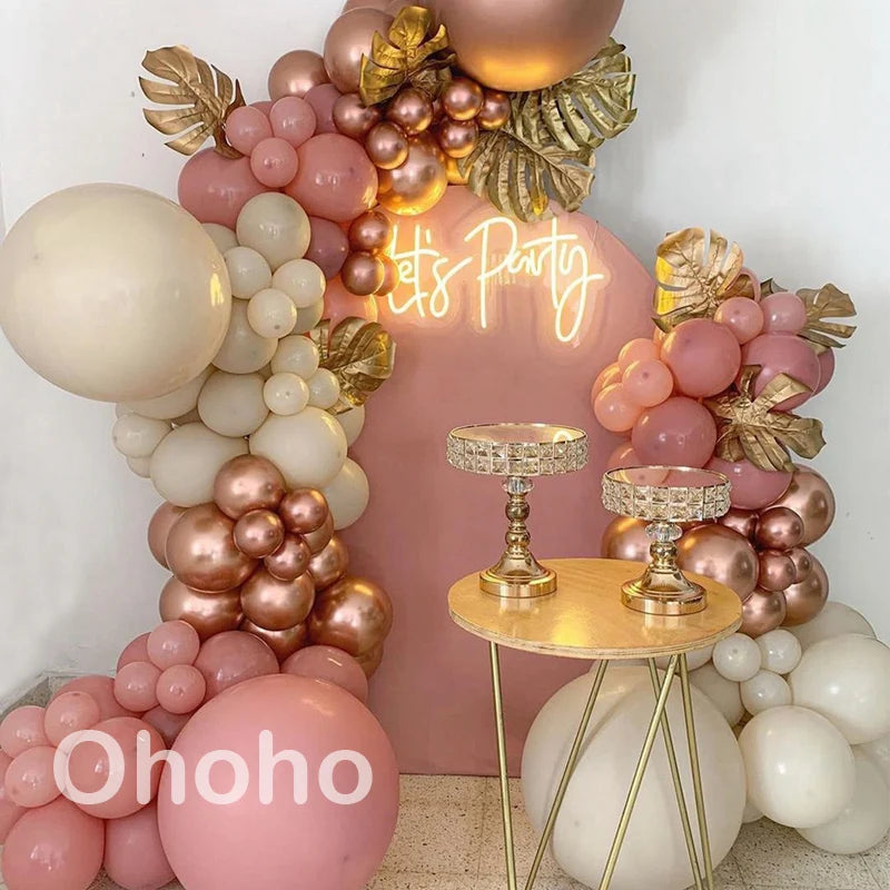 A pink and beige balloon garland arch kit featuring various sized balloons arranged in a decorative display.