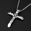 A silver stainless steel cross necklace pendant hanging from a chain against a black background.