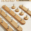 A wooden wall hook rack with four hooks made of solid beech wood is displayed on a light surface.