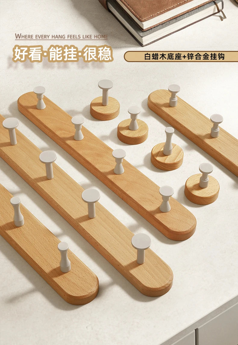 A wooden wall hook rack with four hooks made of solid beech wood is displayed on a light surface.