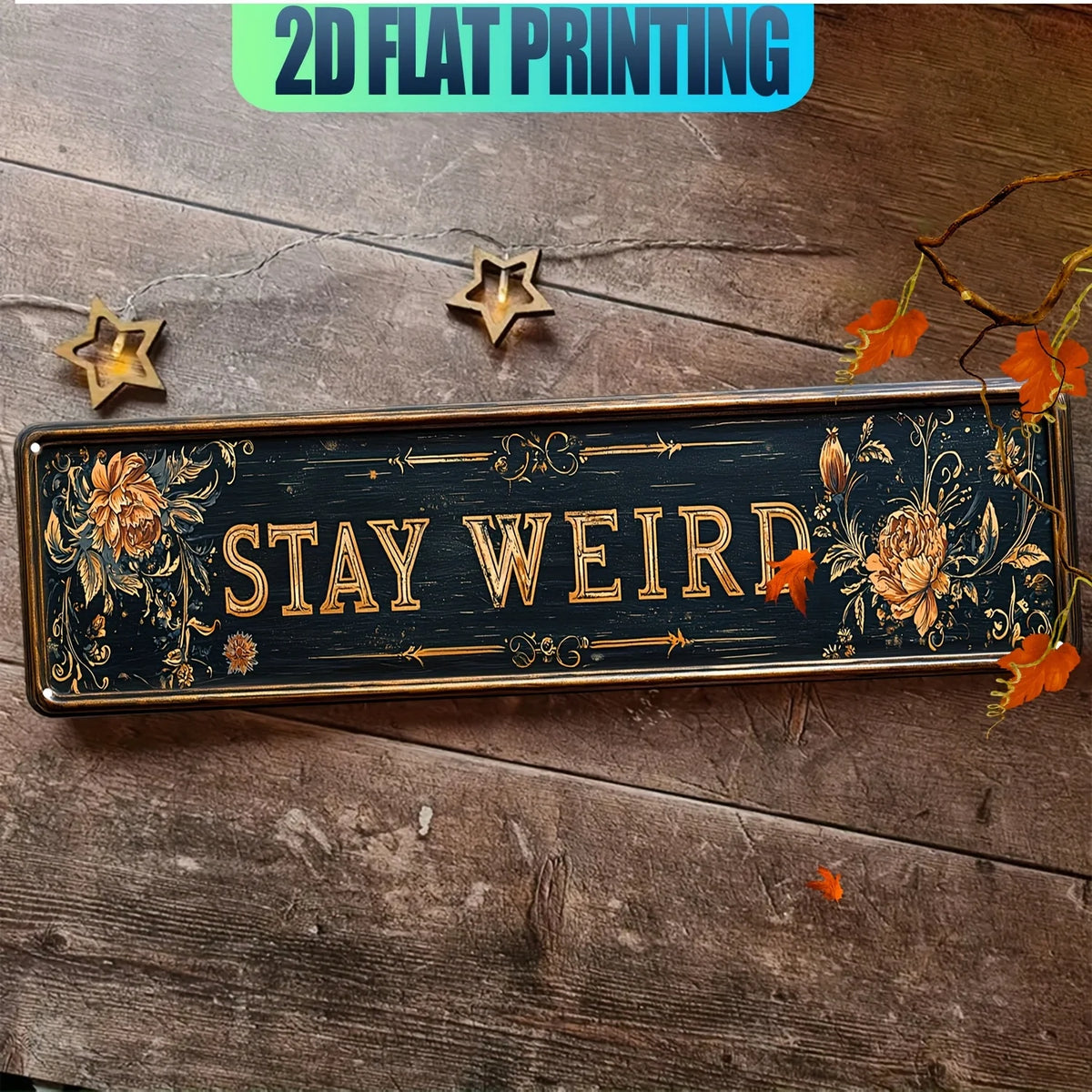 A rectangular metal wall sign with gold lettering and floral designs, featuring the text STAY WEIRD on a dark background.