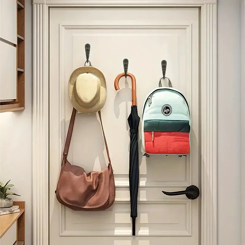 A light blue and green backpack is hanging on a wall hook next to a pink leather shoulder bag.