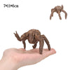 A brown collectible figurine set of Rocky and Grace, shaped like a creature, is held in a person's hand.