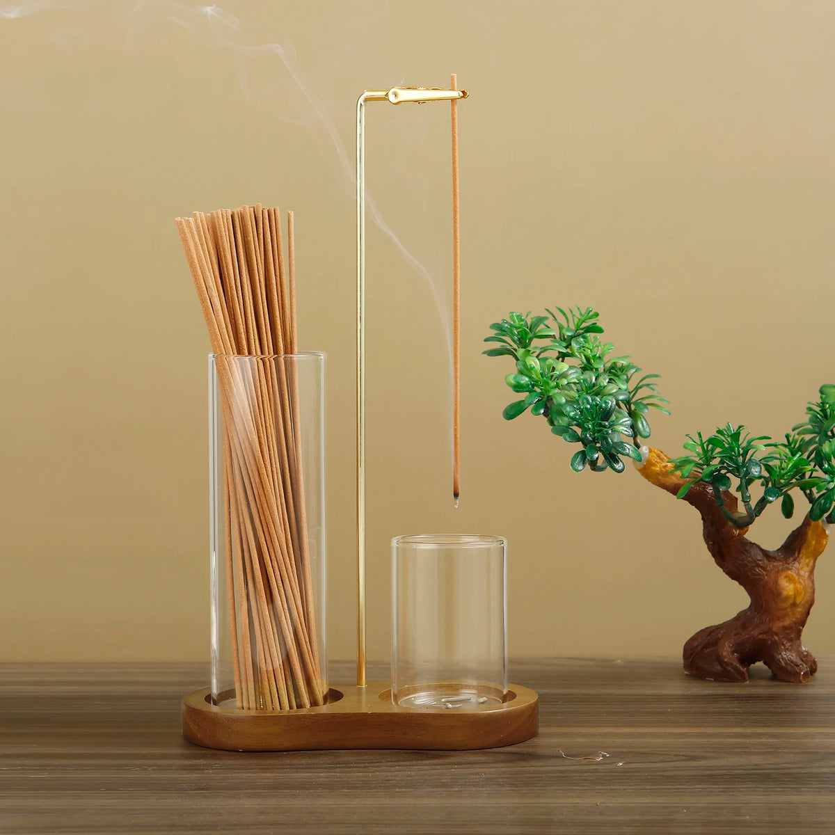 A tall glass incense holder with bamboo sticks and a metal rod is displayed on a wooden surface.