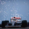 A Formula 1 race car with a driver in the cockpit speeding on a track under a snowy sky.