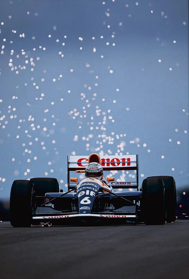 A Formula 1 race car with a driver in the cockpit speeding on a track under a snowy sky.