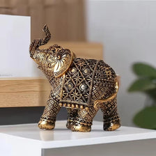A vintage resin elephant ornament with intricate gold detailing, displayed on a white surface.